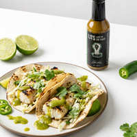 Lime Chili salsa verde hot sauce bottle beside grilled fish tacos with cabbage slaw, cilantro and lime (hover), photo 3