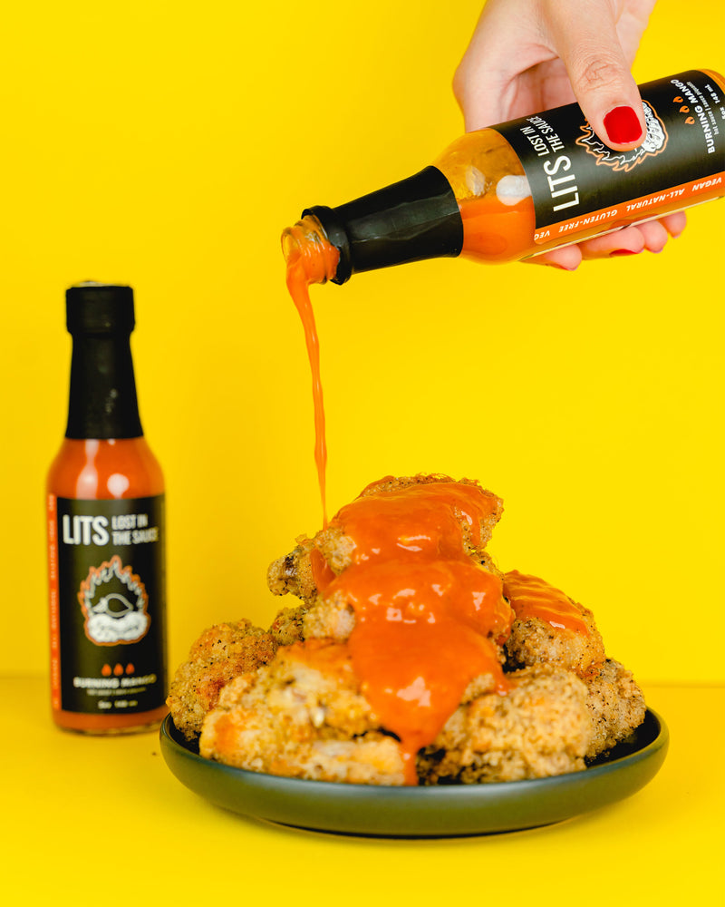 
                  
                    Mango Scotch Bonnet Hot Sauce Pouring Over Plate of Fried Chicken Thighs
                  
                